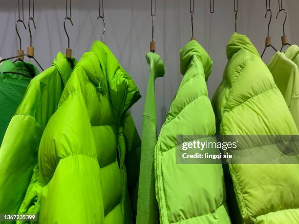 green down jacket hanging on clothes rack - green jacket fashion item 個照片及圖片檔