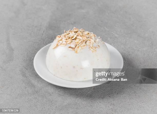 oatmeal cream jelly, panna cotta in the shape of a hemisphere on a plate on a light gray background - mousse stockfoto's en -beelden