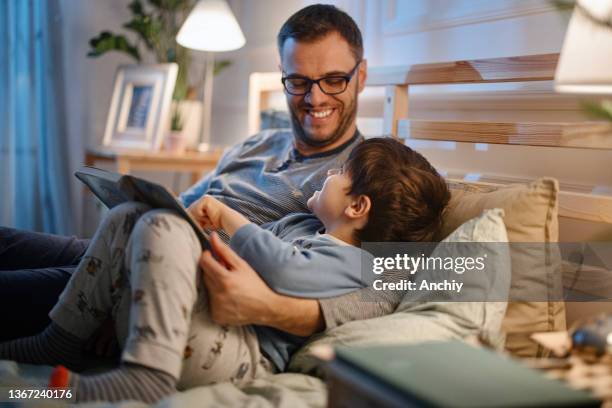 young father reading a bedtime story to his son - boa noite imagens e fotografias de stock