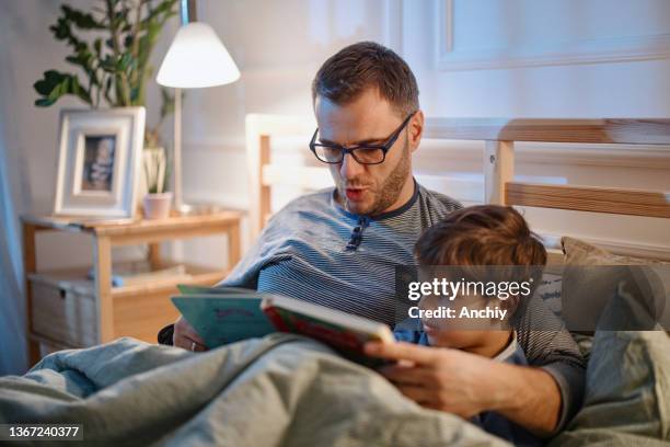 young father reading a bedtime story to his son - tough stock pictures, royalty-free photos & images