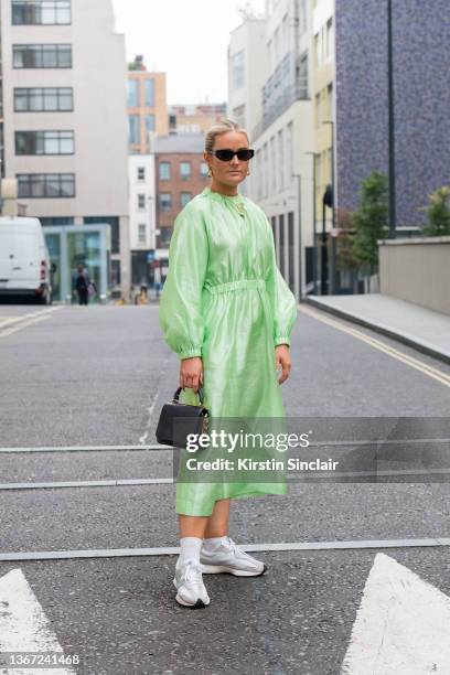 Jessica Kate wears a Stine Goya dress, Anya Hindmarch bag and New Balance trainers during London Fashion Week September 2021 on September 19, 2021 in...