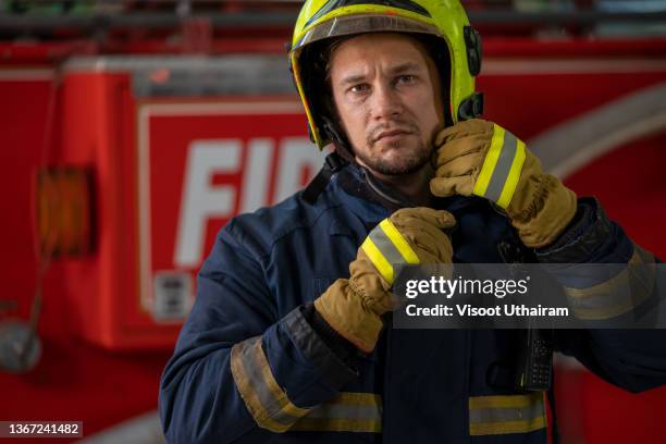 rescue firefighter in safe helmet and uniform standing near fire truck,fireman equipment. - rescue worker photos et images de collection