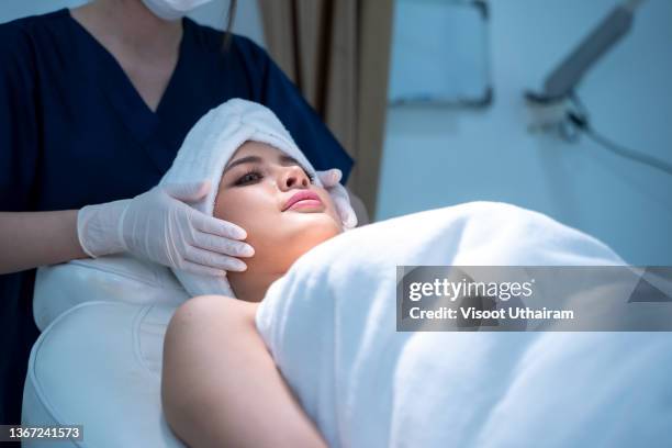 cosmetologist making manual relaxing rejuvenating facial massage for young woman in beauty salon,model and doctor. - festziehen stock-fotos und bilder