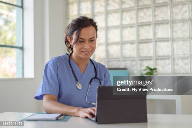 female doctor reviews patient records on tablet computer - virtual healthcare stock pictures, royalty-free photos & images