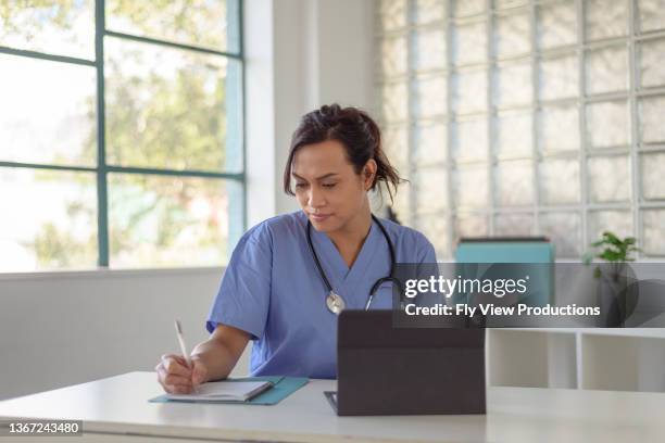 female doctor reviews patient records on tablet computer - medical writer stock pictures, royalty-free photos & images