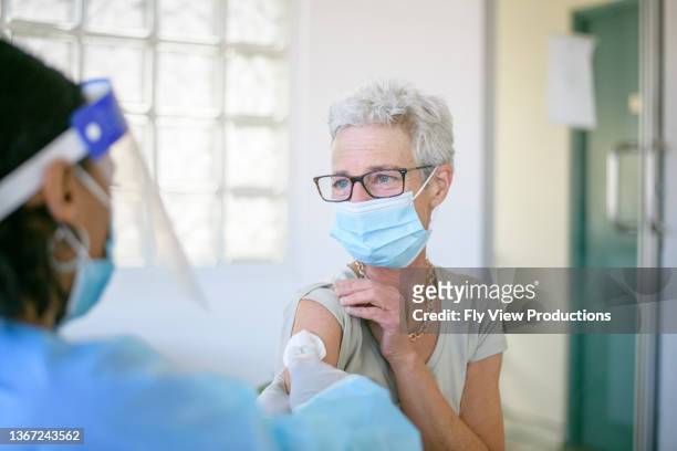 mature adult woman receiving covid-19 vaccine - aussie flu stock pictures, royalty-free photos & images