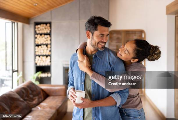 pareja amorosa en casa abrazándose y luciendo muy feliz - relación humana fotografías e imágenes de stock
