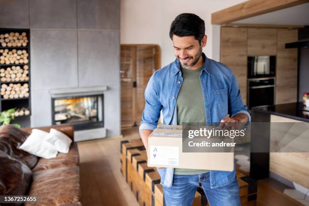 happy man receiving a package at home - receiving delivery stock pictures, royalty-free photos & images