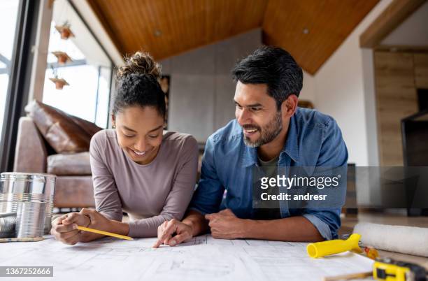 couple remodeling their house and looking at  blueprints - renovatie begrippen stockfoto's en -beelden