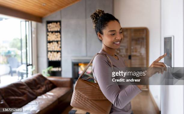 mujer activando la alarma mientras sale de su hogar inteligente - connected home fotografías e imágenes de stock