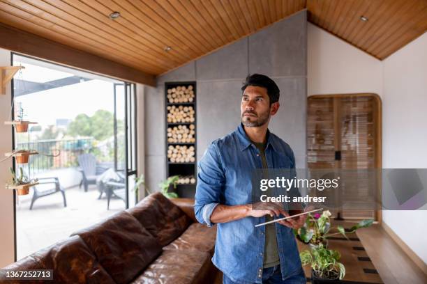 man controlling the lights of his smart home with a tablet - smart homes stock pictures, royalty-free photos & images