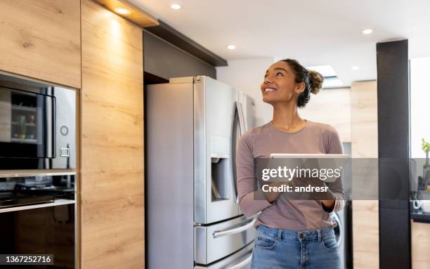 mujer controlando las luces de su casa inteligente utilizando un sistema automatizado - connected home fotografías e imágenes de stock