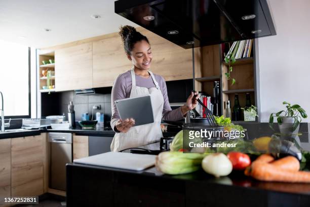 happy woman cooking at home following an online recipe - following recipe stock pictures, royalty-free photos & images