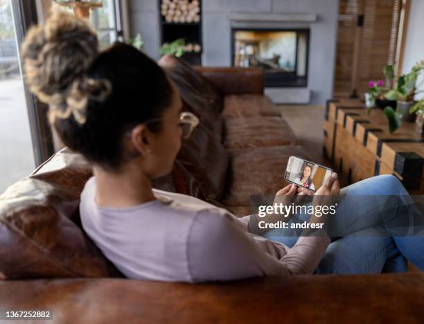 sick woman at home talking to a doctor on a video call - doctor house call stock pictures, royalty-free photos & images