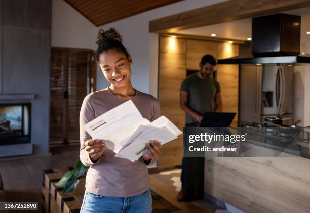 mujer en casa mirando una factura de servicios públicos que llegó por correo - e post fotografías e imágenes de stock