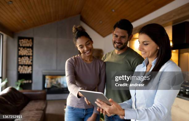 real estate agent showing a house to a couple - real estate broker stock pictures, royalty-free photos & images