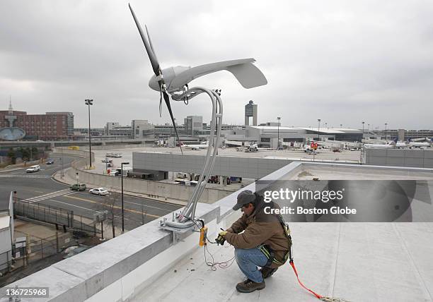 Jorge Andrade, a technical specialist for Aero Vironment, helps to install one of several 6-foot wind turbines on the roof of the Logan Airport...