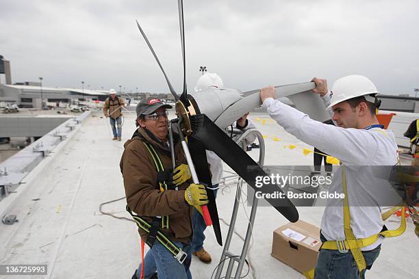 Jorge Andrade, left, a technical specialist for Aero Vironment, and Kenny Wilson, right, of Groom Energy help to install one of several 6-foot wind...