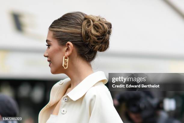 Amelie Zilber wears a gold large pendant earring from Fendi, a white shoulder-off short dress, a white latte jacket from Fendi, outside Fendi, during...