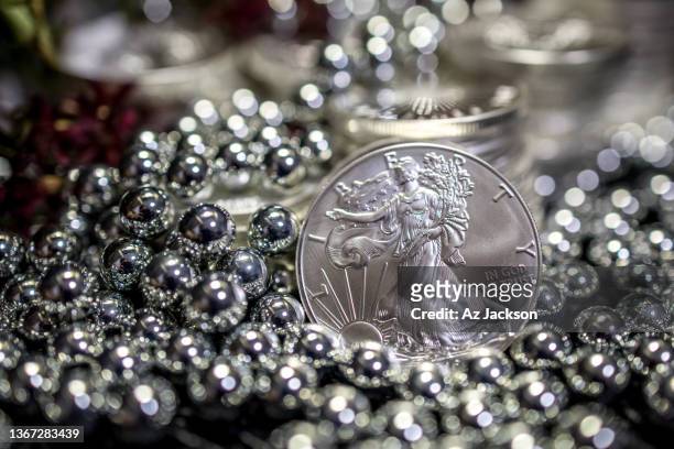 the american liberty silver coin featured among piles of silver ball bearings - bearings metal stock pictures, royalty-free photos & images
