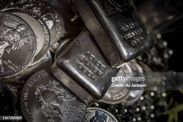 a pile of silver bullion bars and coins against a dark background - zilverkleurig stockfoto's en -beelden