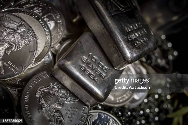 a pile of silver bullion bars and coins against a dark background - silver colored stock pictures, royalty-free photos & images