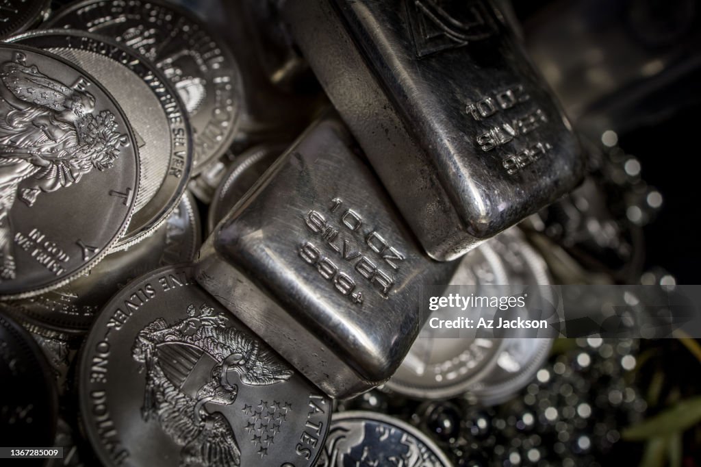 A pile of Silver bullion bars and coins against a dark background