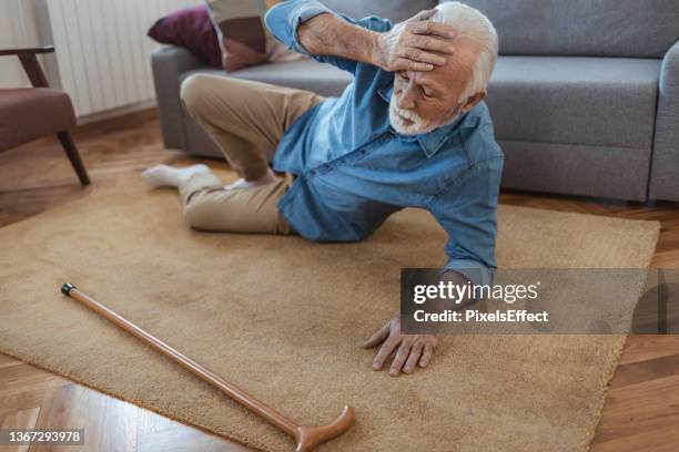 disabled senior man lying on carpet - gevallen stockfoto's en -beelden