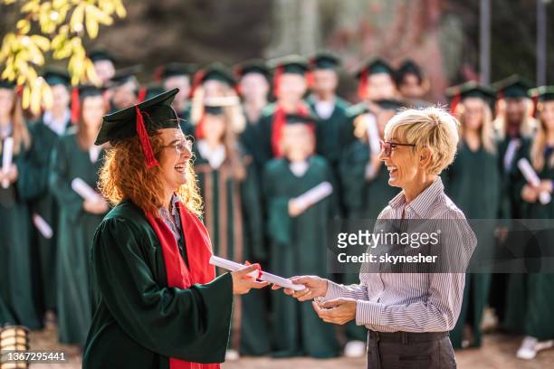happy senior professor giving diploma to female student on graduation day. - dean stock pictures, royalty-free photos & images