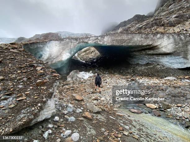 person standing in front of melting glacier bridge - vorarlberg imagens e fotografias de stock