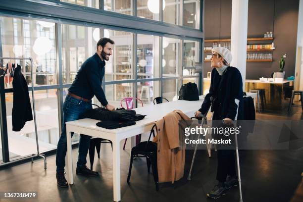 female entrepreneur with disability talking to male colleague in office - crutches fotografías e imágenes de stock