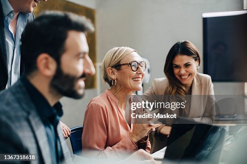 Happy business people discussing during meeting in board room at corporate office Happy business people discussing during meeting in board room at corporate office