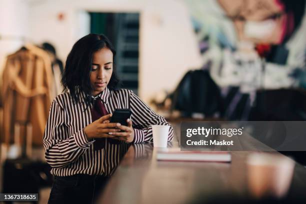 female professional using smart phone at table in office - nuova normalità concetto foto e immagini stock