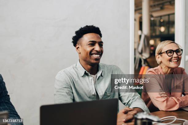 happy male professionals sitting by female colleague in meeting at office board room - masculine office black white photos et images de collection