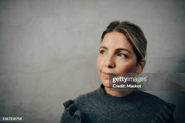 contemplative businesswoman looking away against wall - employee headshot stock pictures, royalty-free photos & images