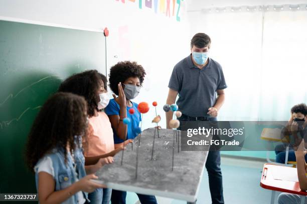 girls doing a presentation about the solar system in the classroom - using a face mask - brazilian female models 個照片及圖片檔