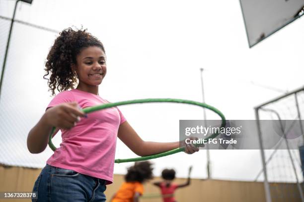 girl playing with hula hoop at a sports court - hooping stock pictures, royalty-free photos & images