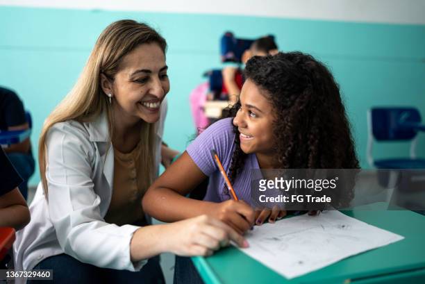 teacher helping a student with a lesson in the classroom - brasile stock pictures, royalty-free photos & images