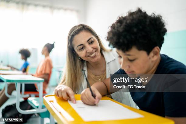 insegnante che aiuta uno studente con una lezione in classe - schoolboy foto e immagini stock