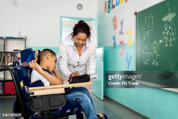 teacher teaching a boy with special needs in the classroom - special education stock pictures, royalty-free photos & images