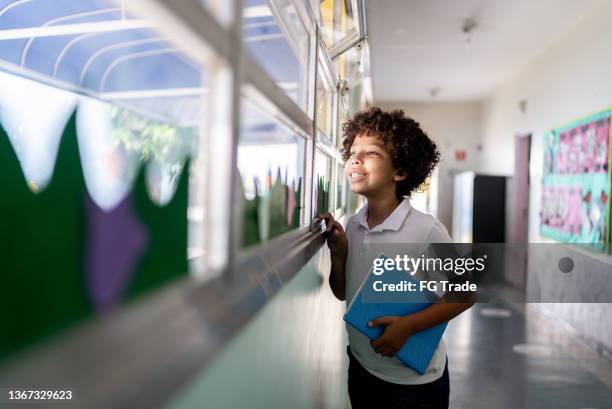 niño mirando por la ventana de la escuela - one boy only fotografías e imágenes de stock