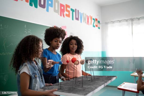 girls doing a presentation about the solar system in the classroom - kid presenting stockfoto's en -beelden