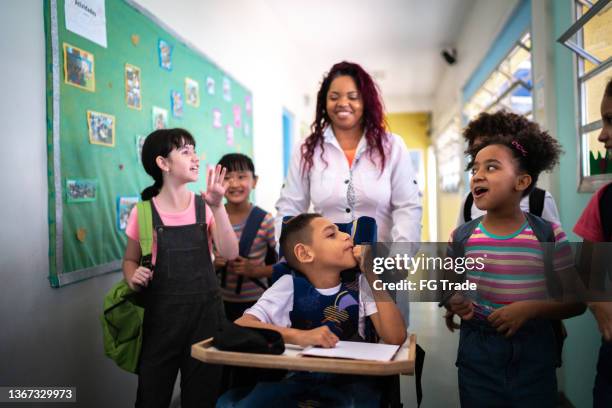 maestro y estudiantes caminando en el pasillo de la escuela, incluida una persona con necesidades especiales - diversidad funcional fotografías e imágenes de stock