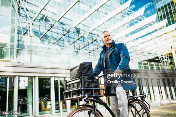 mature businessman commuting by bicycle. eco friendly living in the city - cycling netherlands stock pictures, royalty-free photos & images