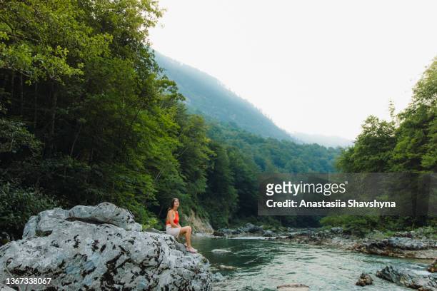 female traveler sitting on the rock inside the scenic mountain canyon in montenegro - skimpy bathing suits stock pictures, royalty-free photos & images
