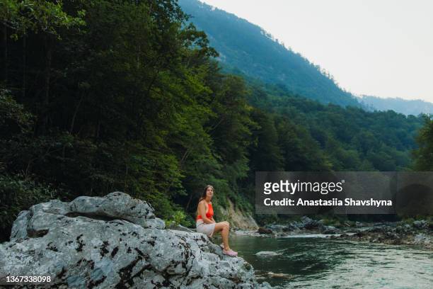 female traveler sitting on the rock inside the scenic mountain canyon in montenegro - women in skimpy bathing suits stock pictures, royalty-free photos & images