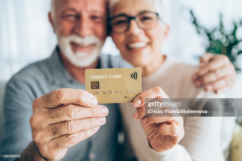 Happy couple holding a credit card.