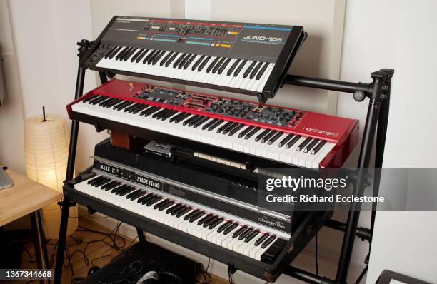 Keyboards on stand in recording studio including Roland Juno 106 synthesizer, Nord Stage 2 and Fender Rhodes electric piano, London, 2016.