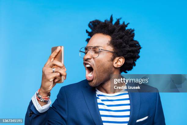 portrait of angry man using mobile phone - angry on phone stockfoto's en -beelden