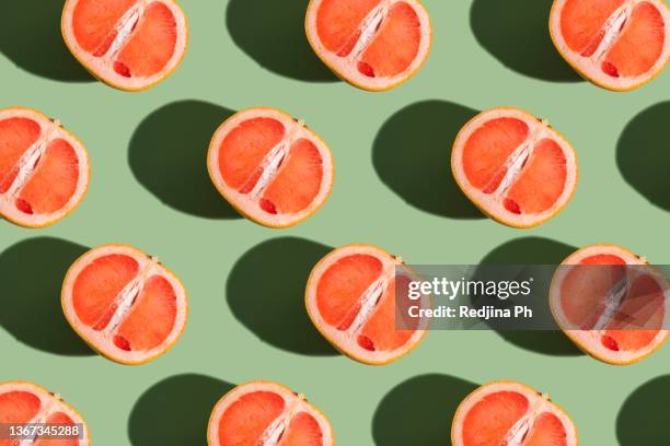 a pattern of half a grapefruit on a green background with a hard shadow. - grapefruit bildbanksfoton och bilder